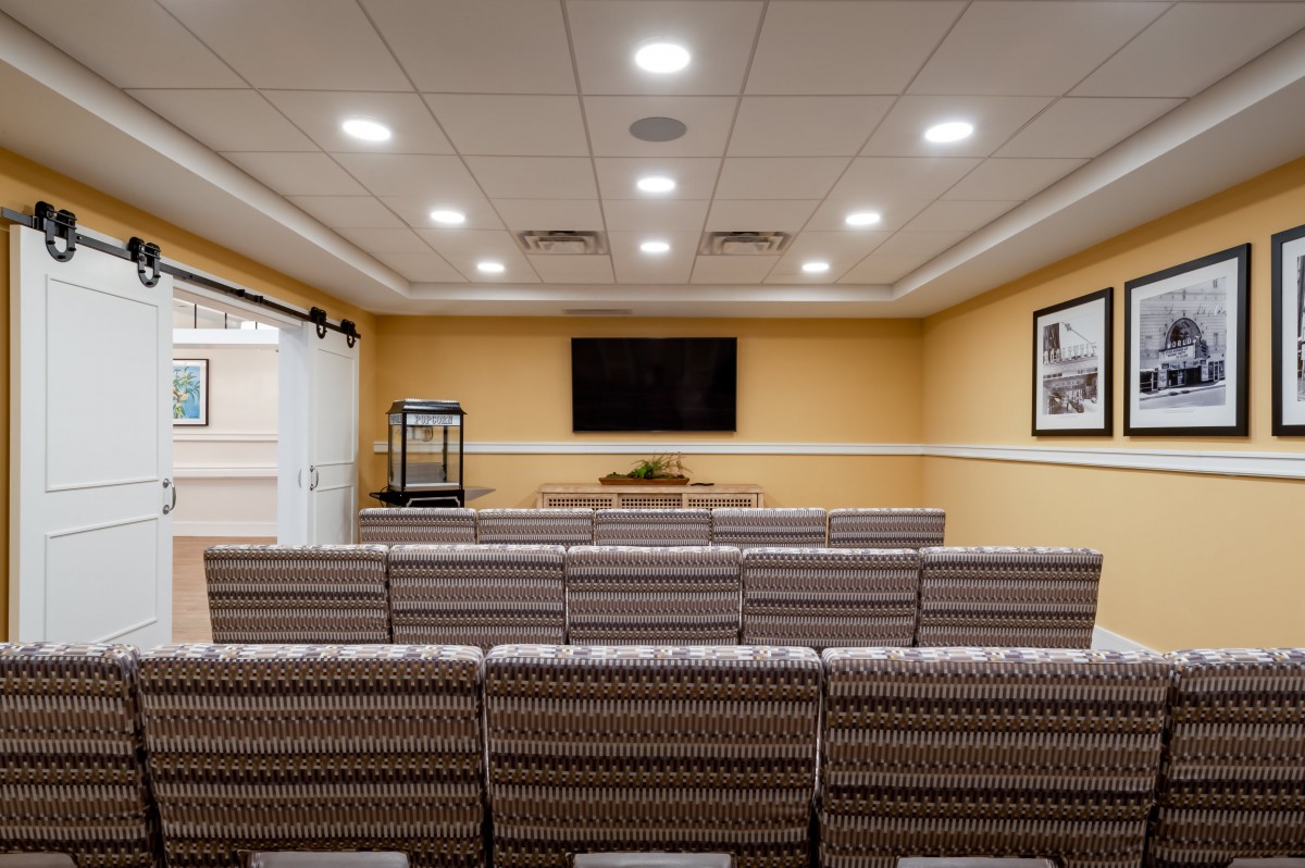 A well-lit meeting room with rows of seats facing a television screen, suitable for presentations or conferences.