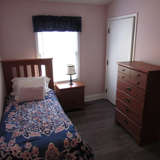 A cozy and well-furnished bedroom featuring a single bed, nightstand, and dresser.