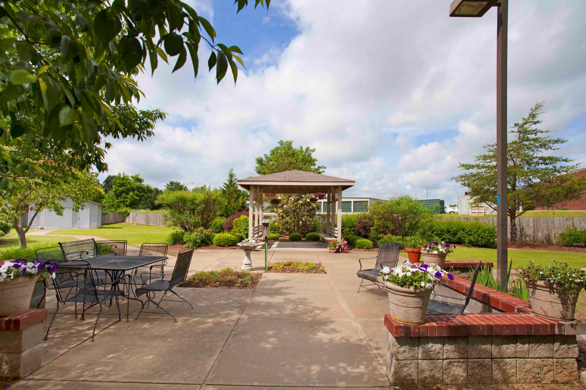 A tranquil patio and garden area with a gazebo surrounded by lush greenery.