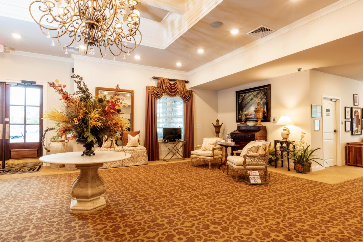 An elegantly decorated living room with a chandelier, plush seating, and warm-toned decor.