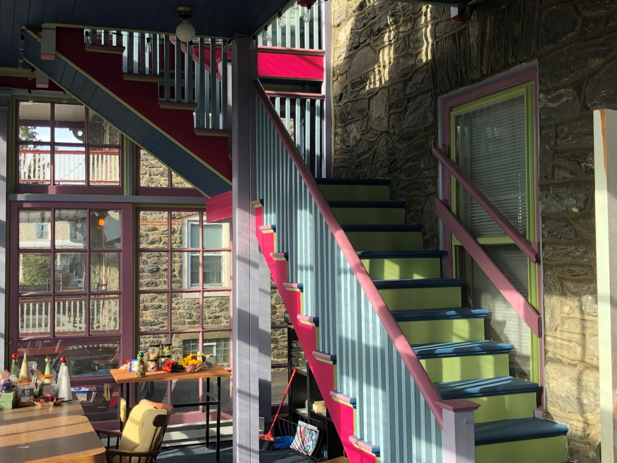 A brightly colored interior featuring a staircase with vibrant accents, bathed in sunlight.