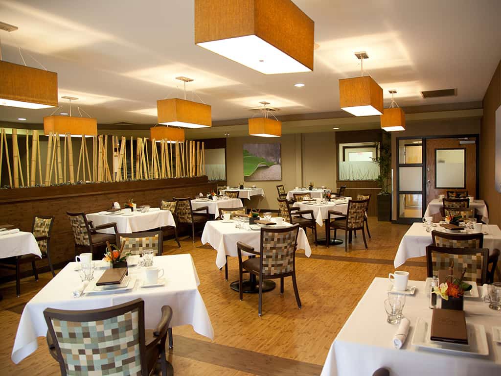 A modern and elegantly designed restaurant interior featuring neatly arranged tables and chairs, with warm lighting creating a welcoming ambience.