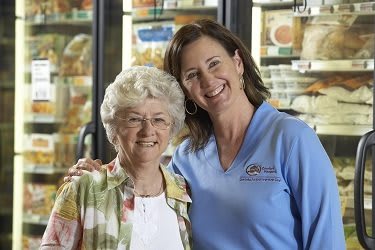 Two women smiling together at a grocery store.
