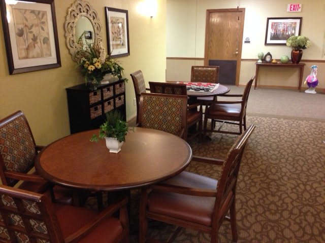 A cozy dining area with several tables and chairs, decorated with artwork and plants.