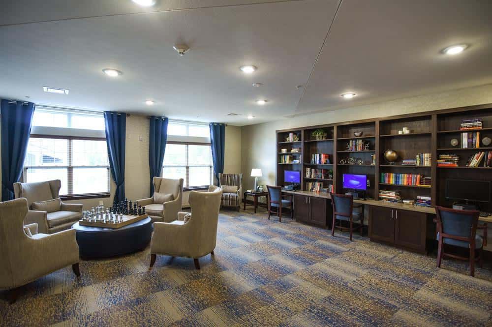 A cozy library space with bookshelves, computers, and comfortable seating.