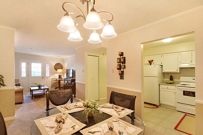 A cozy dining area with a view into the kitchen, featuring elegant lighting and a neatly set table.