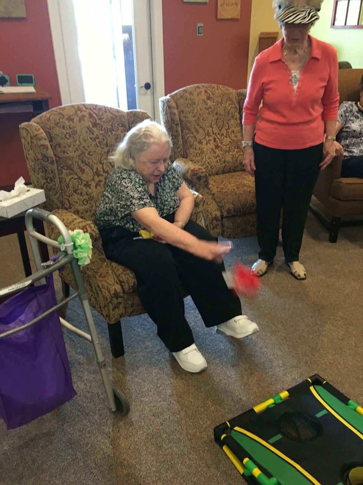 An elderly woman participates in an indoor activity at an assisted living facility.