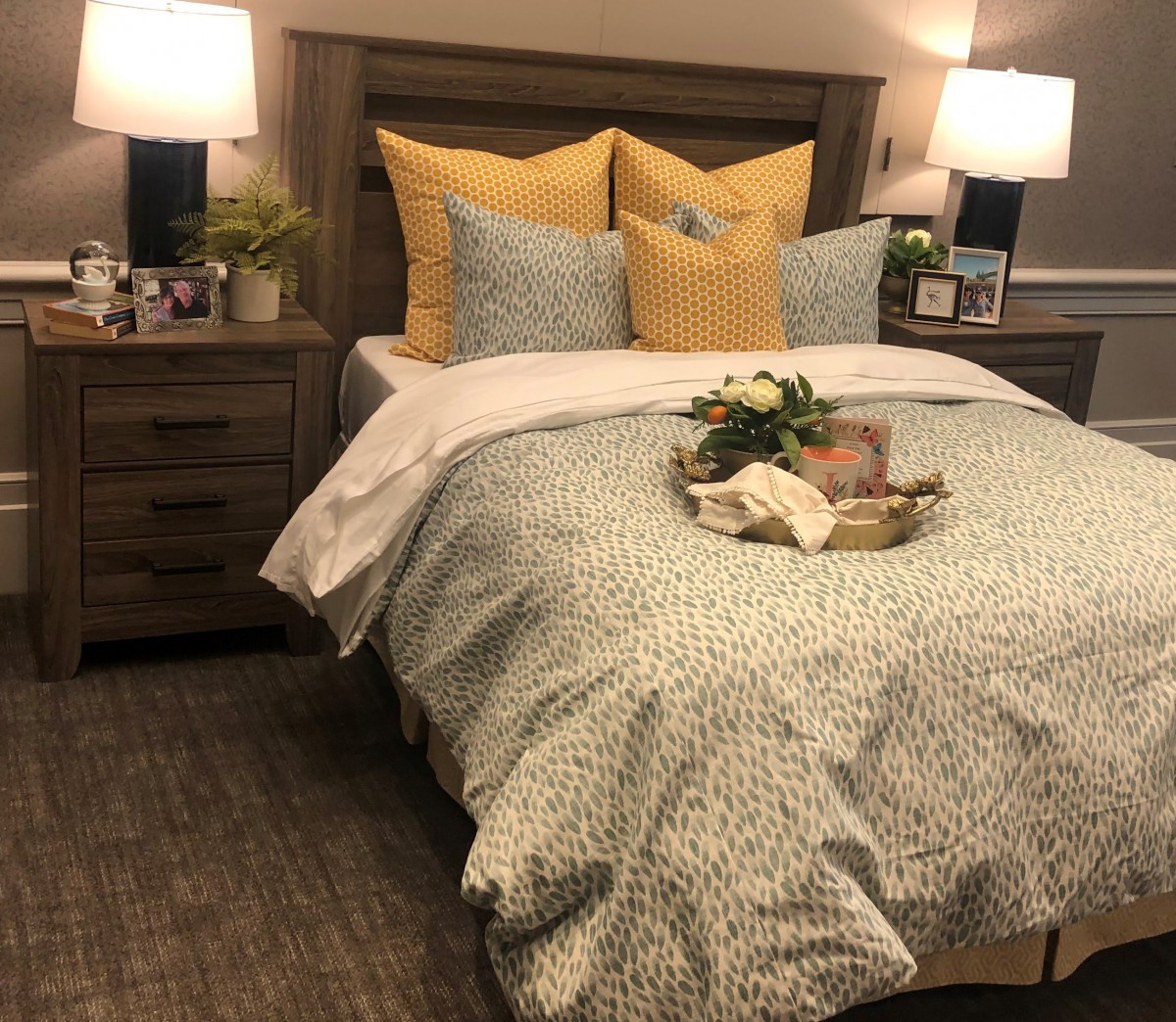 A cozy bedroom interior with patterned bedding and accent pillows, featuring bedside lamps on wooden nightstands.
