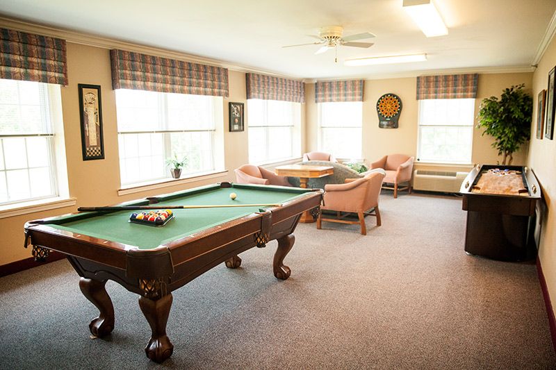 A cozy game room featuring a pool table and comfortable seating areas with large windows.