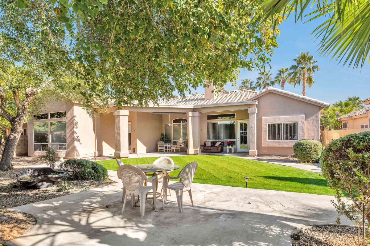 A serene backyard with a patio set, well-kept lawn, and shaded by trees.