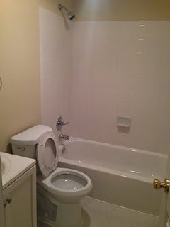 A view of a simple bathroom featuring a toilet, bathtub, and sink.