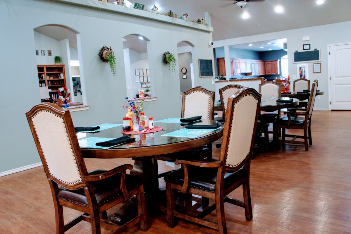 A cozy dining room with elegant chairs and a round wooden table, accented by homey decor and warm lighting.