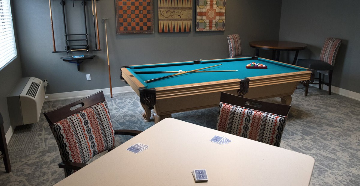 A cozy game room featuring a pool table and playing cards on a nearby table.