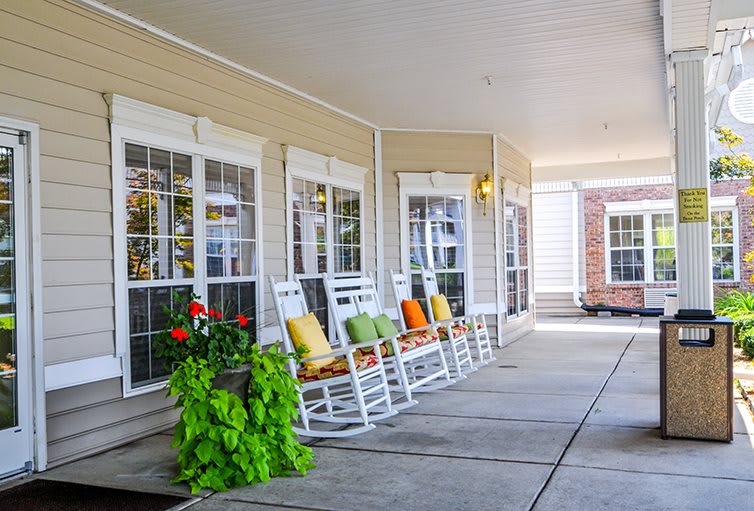 A cozy porch with rocking chairs and vibrant pillows, adorned with lush plants.