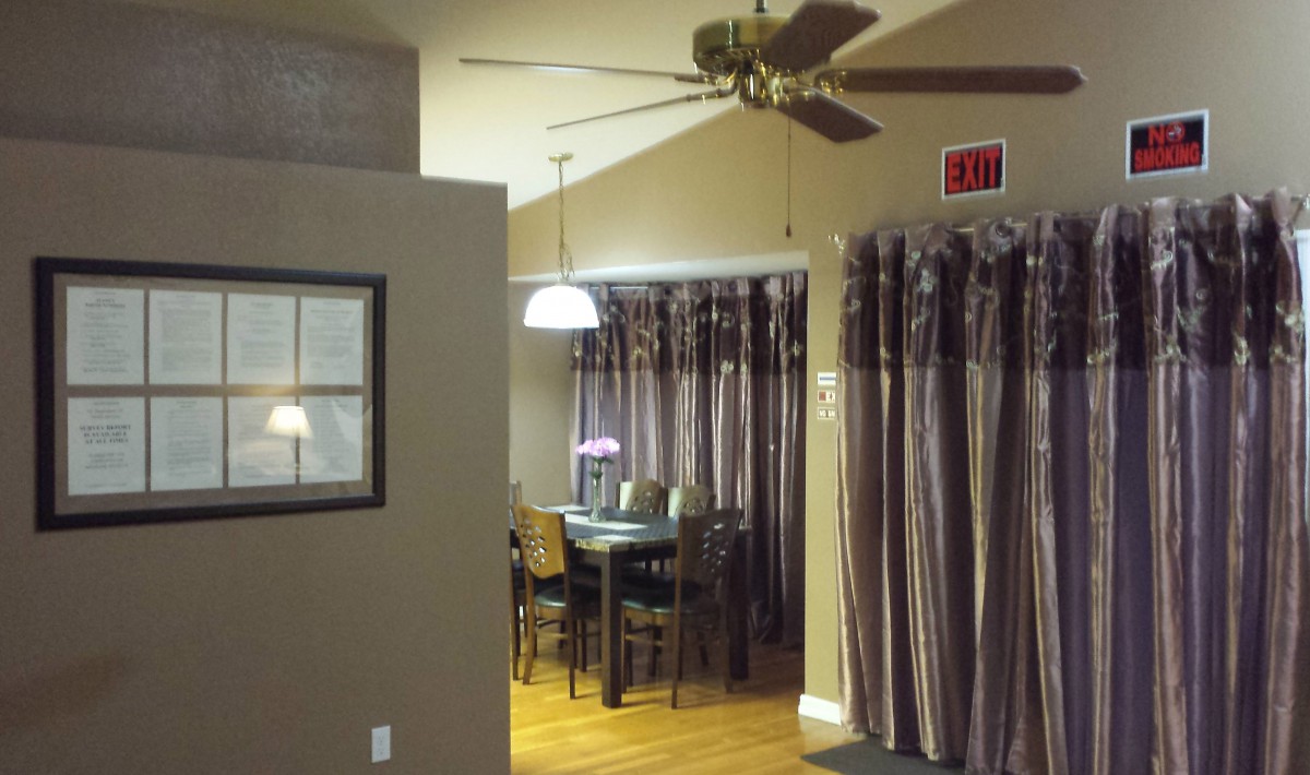 A cozy dining area with a ceiling fan, curtains, and a hanging light fixture over the table.