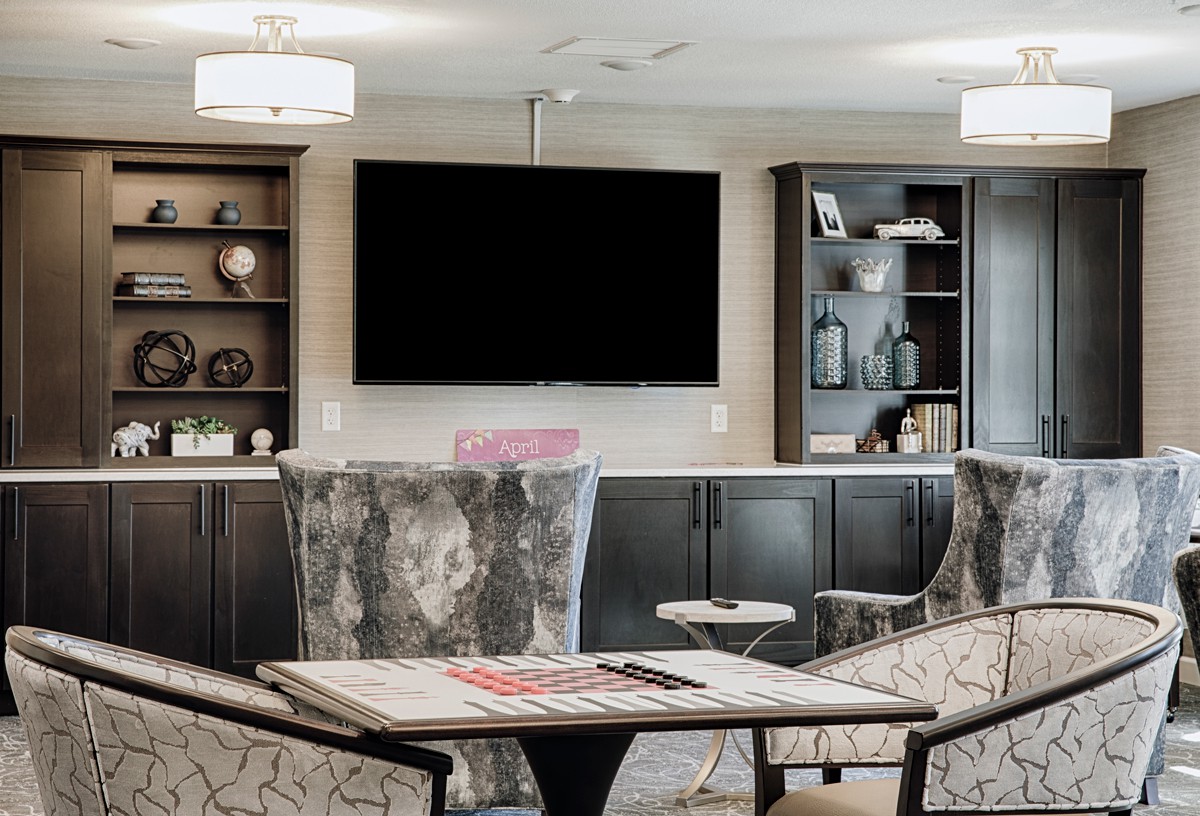 A modern living room with comfortable seating, a large television, and decorative shelves.