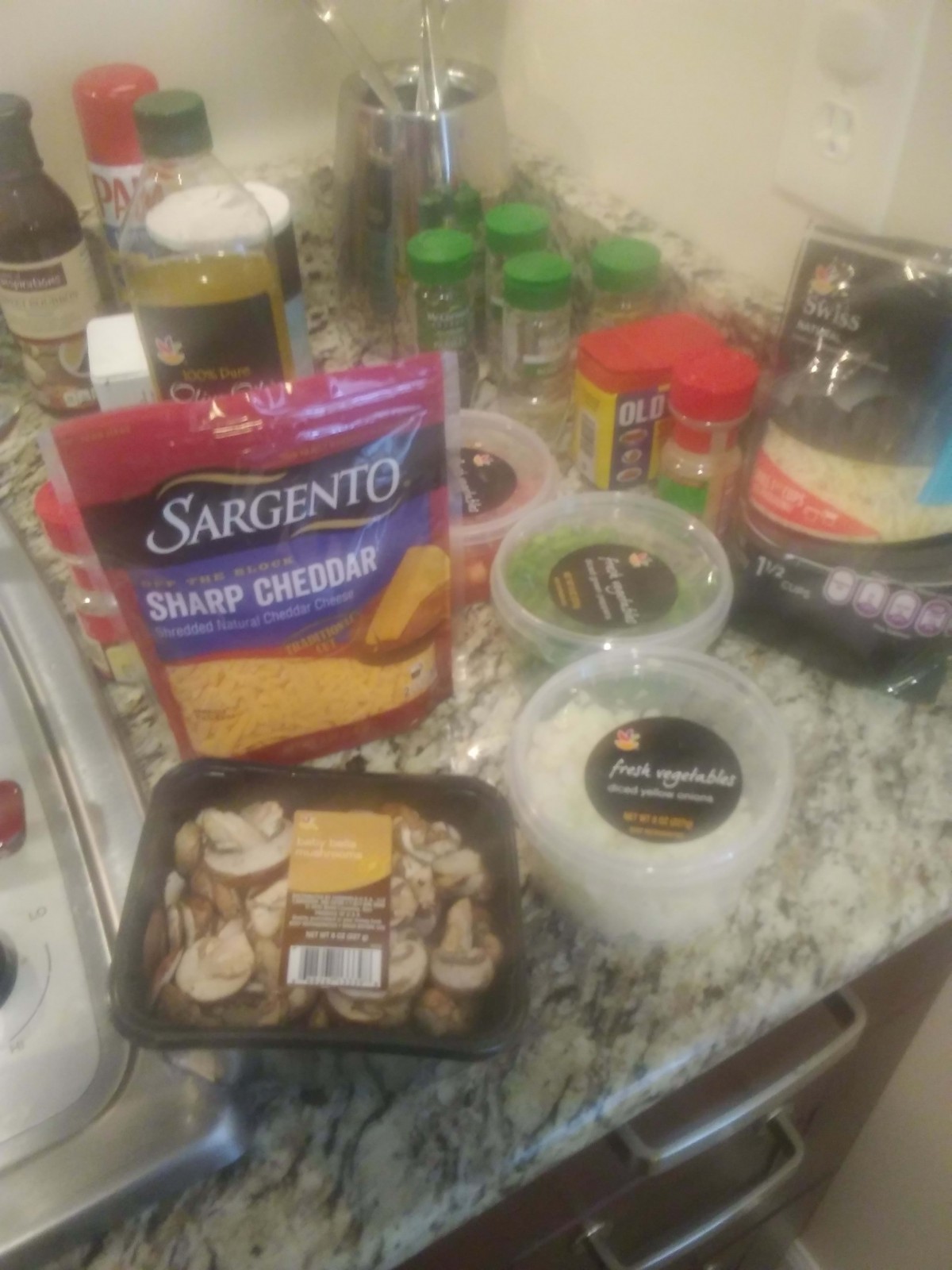 A variety of ingredients, including cheese and mushrooms, are laid out on a kitchen counter for meal preparation.