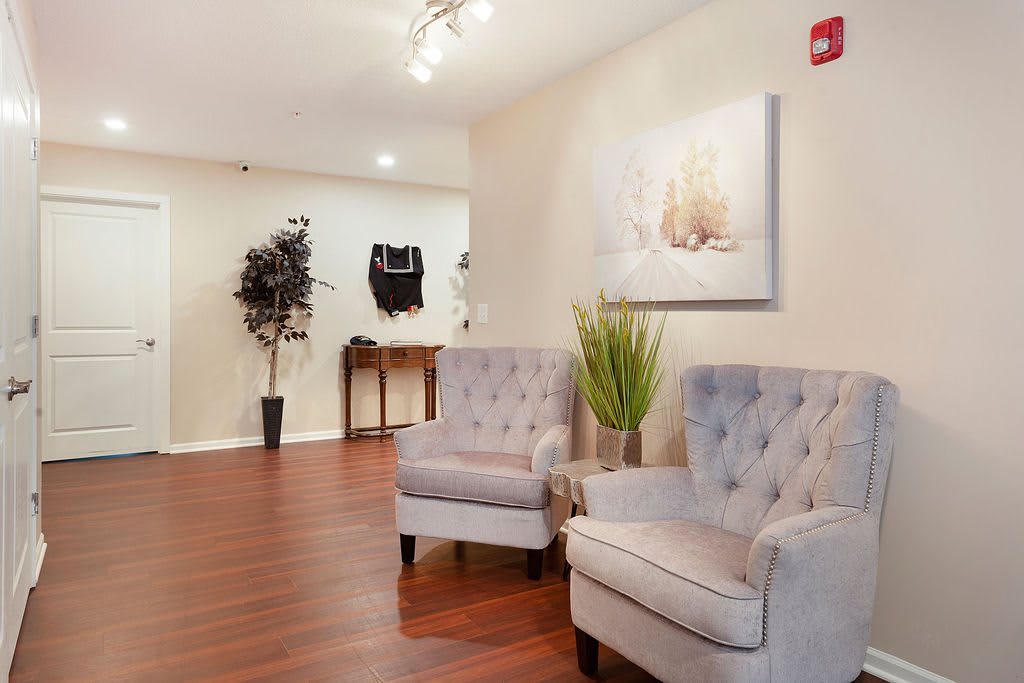 A cozy waiting area with plush chairs, artwork on the wall, and warm wooden flooring.