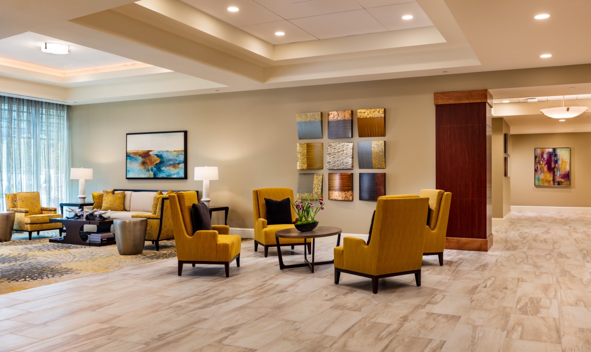 A modern lobby with yellow armchairs, decorative artwork, and a sleek design.