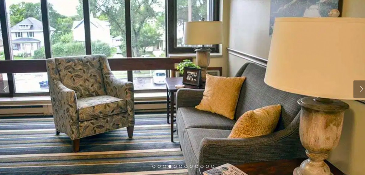 A cozy living room with a sofa, armchair, and coffee table near a large window.