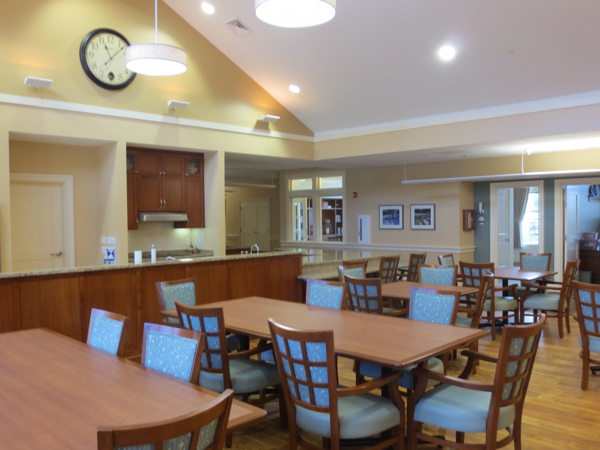 A cozy dining area with multiple tables and chairs arranged neatly under warm lighting.