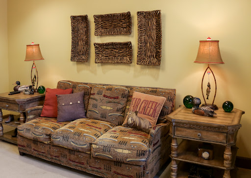 A cozy living room setup featuring a patterned couch, decorative art on the wall, and stylish lamps.