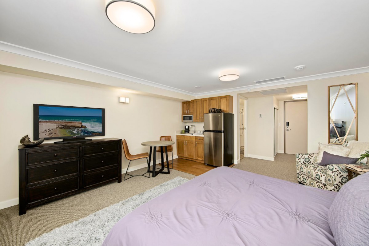A cozy studio apartment with a kitchenette, dining area, and bedroom space.