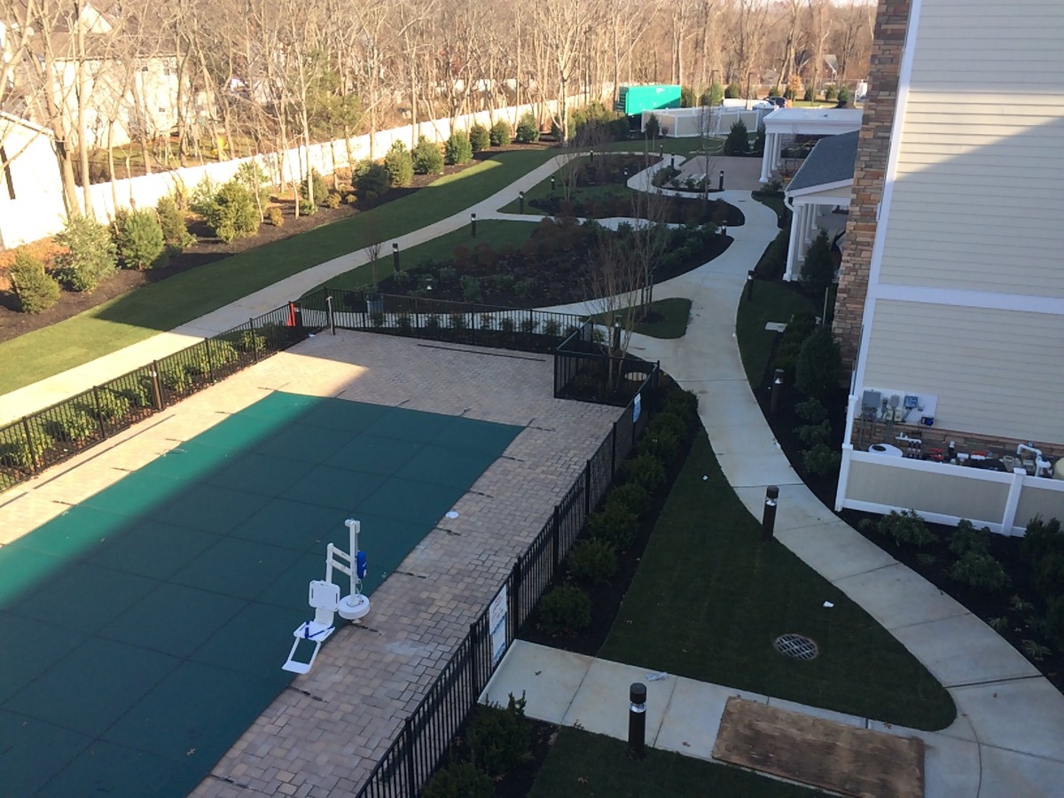 Aerial view of a landscaped garden with a covered pool and winding pathways.