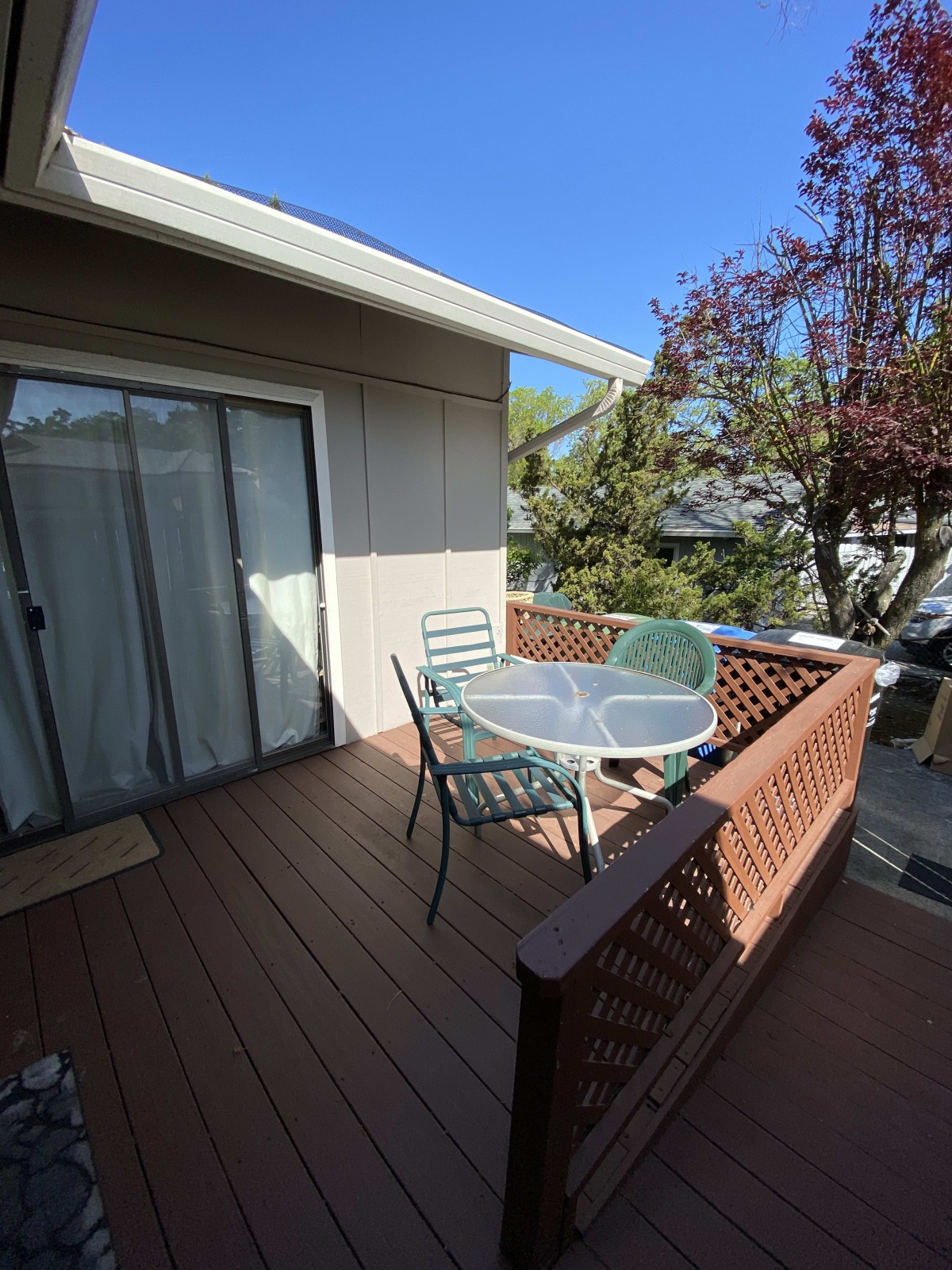 A sunny outdoor deck with patio furniture and a bright blue sky.