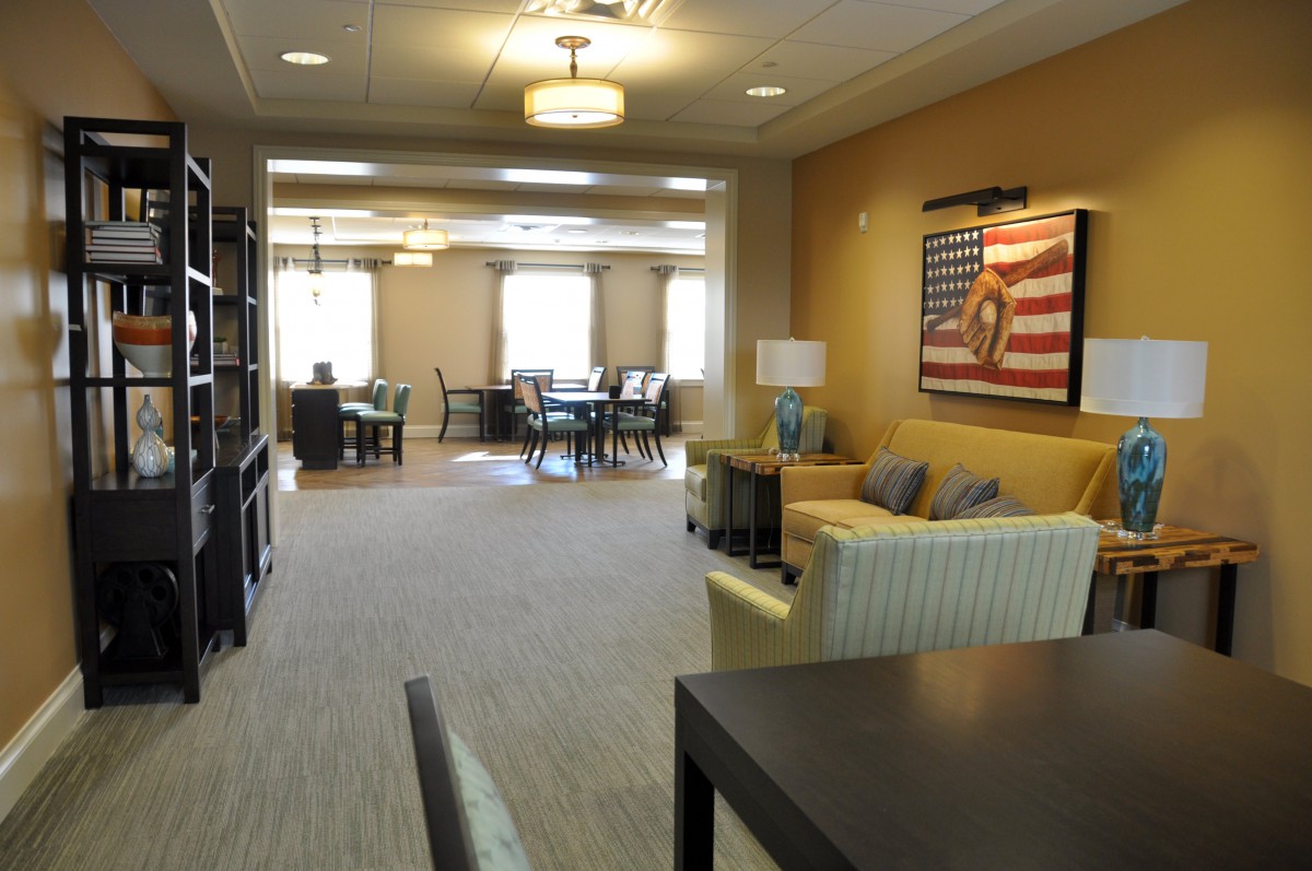 A spacious lounge area with comfortable seating, tables, and artwork on the wall.