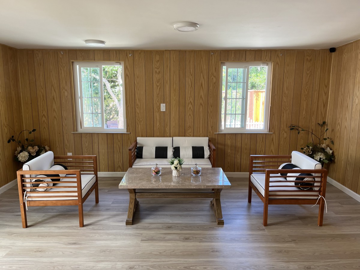 A minimalist living room with wood paneling, featuring a sofa, two chairs, and a coffee table.