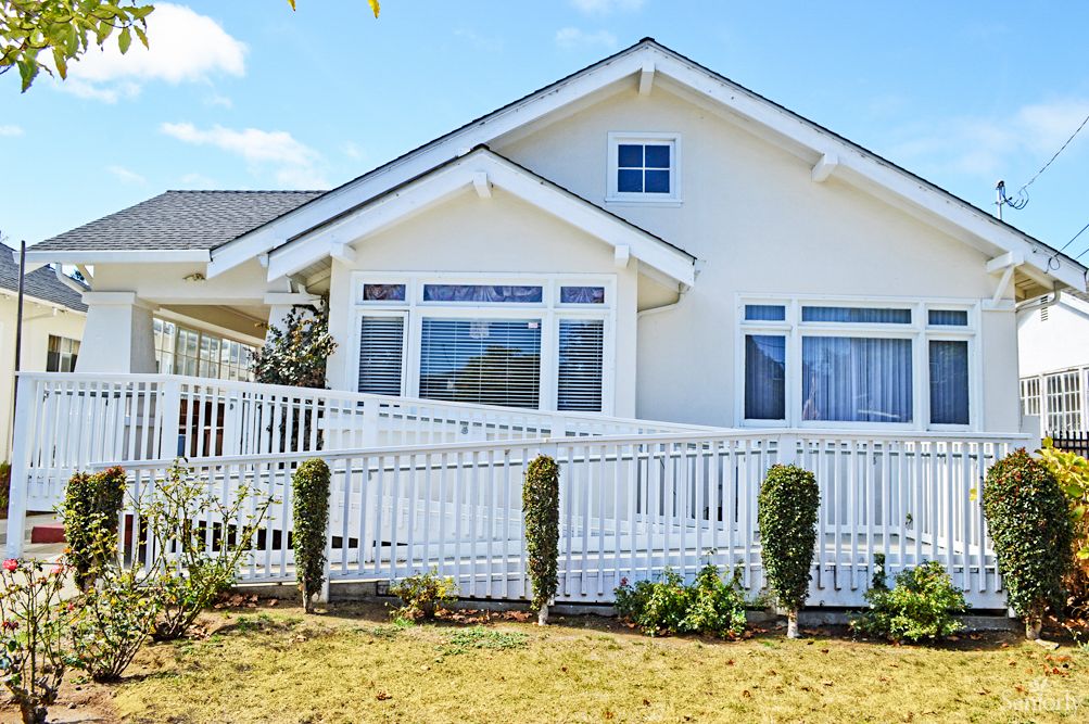A charming white house with a front yard and white picket fence.