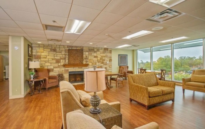A cozy lobby area with comfortable seating, a stone fireplace, and large windows providing natural light.