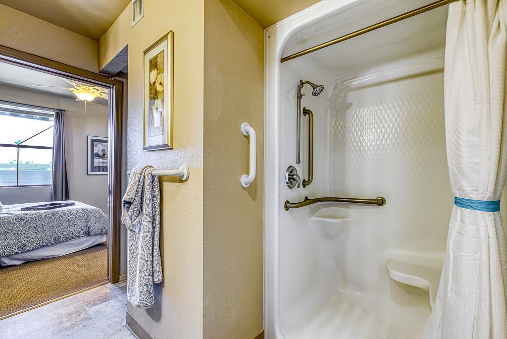 An accessible bathroom with a shower equipped with grab bars and neatly hung towels near the entrance.