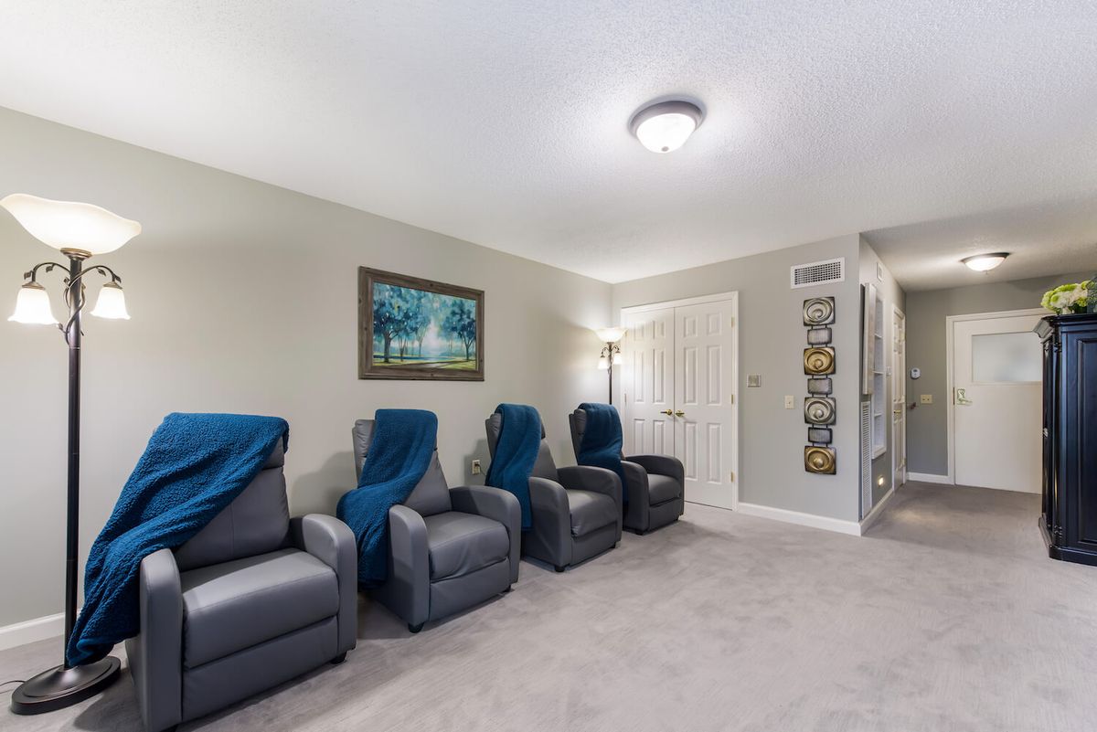 A cozy home theater setup featuring four recliner chairs with blankets, complemented by wall art and soft lighting.