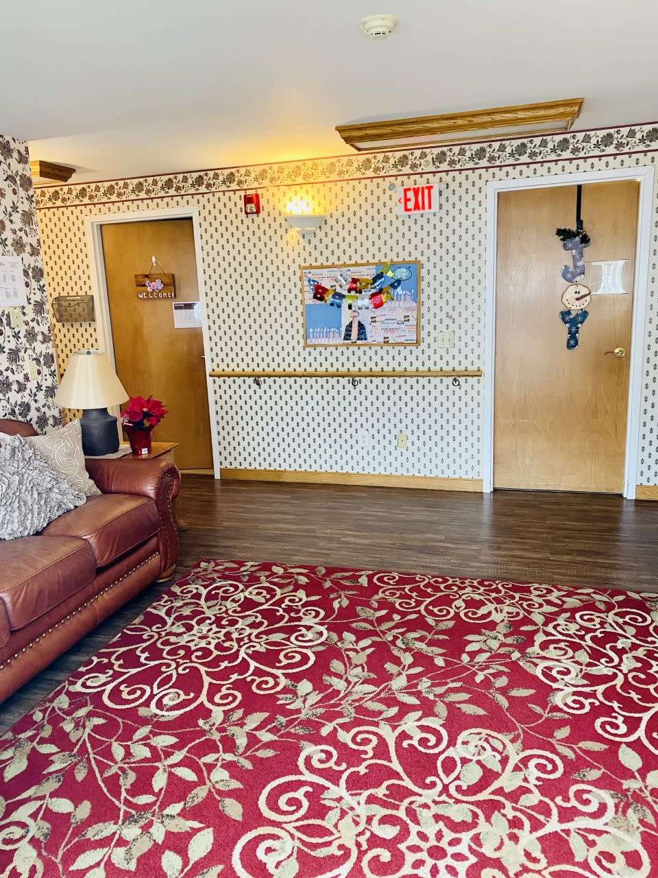 A cozy lobby area with a patterned carpet, couch, and decorated doors.
