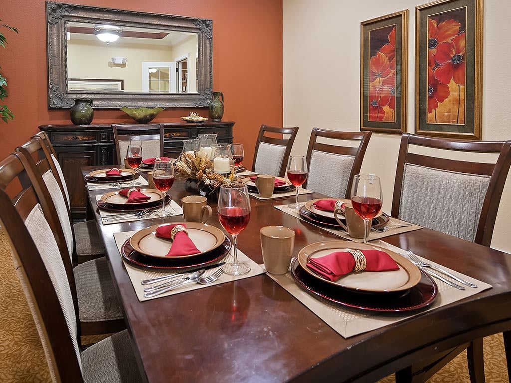 A beautifully set dining table with red napkins and wine glasses, surrounded by elegant decor and artwork.