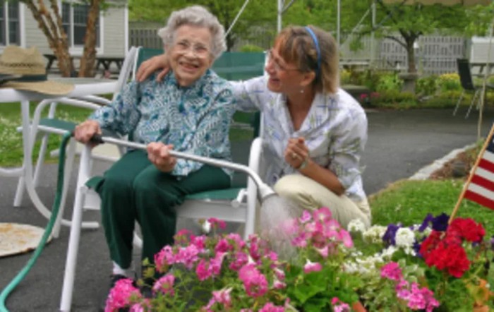 An elderly person and a caregiver enjoying time together in a garden.