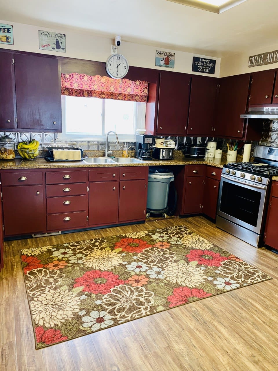 A cozy kitchen with dark cabinets and a colorful rug.