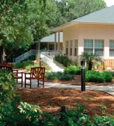 A tranquil outdoor garden area with chairs and a modern building in the background.