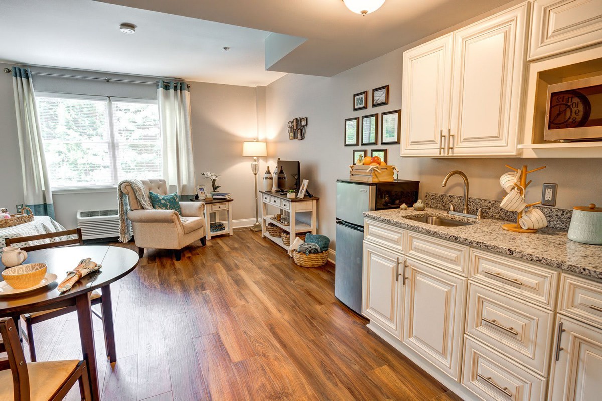A cozy apartment with a kitchenette and living area featuring hardwood floors and stylish decor.