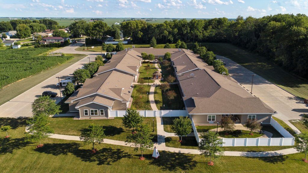 An aerial view of residential buildings with a central pathway surrounded by lawns and trees.