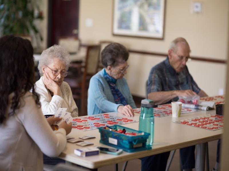 A group of elderly individuals engaged in a card game at a community center.