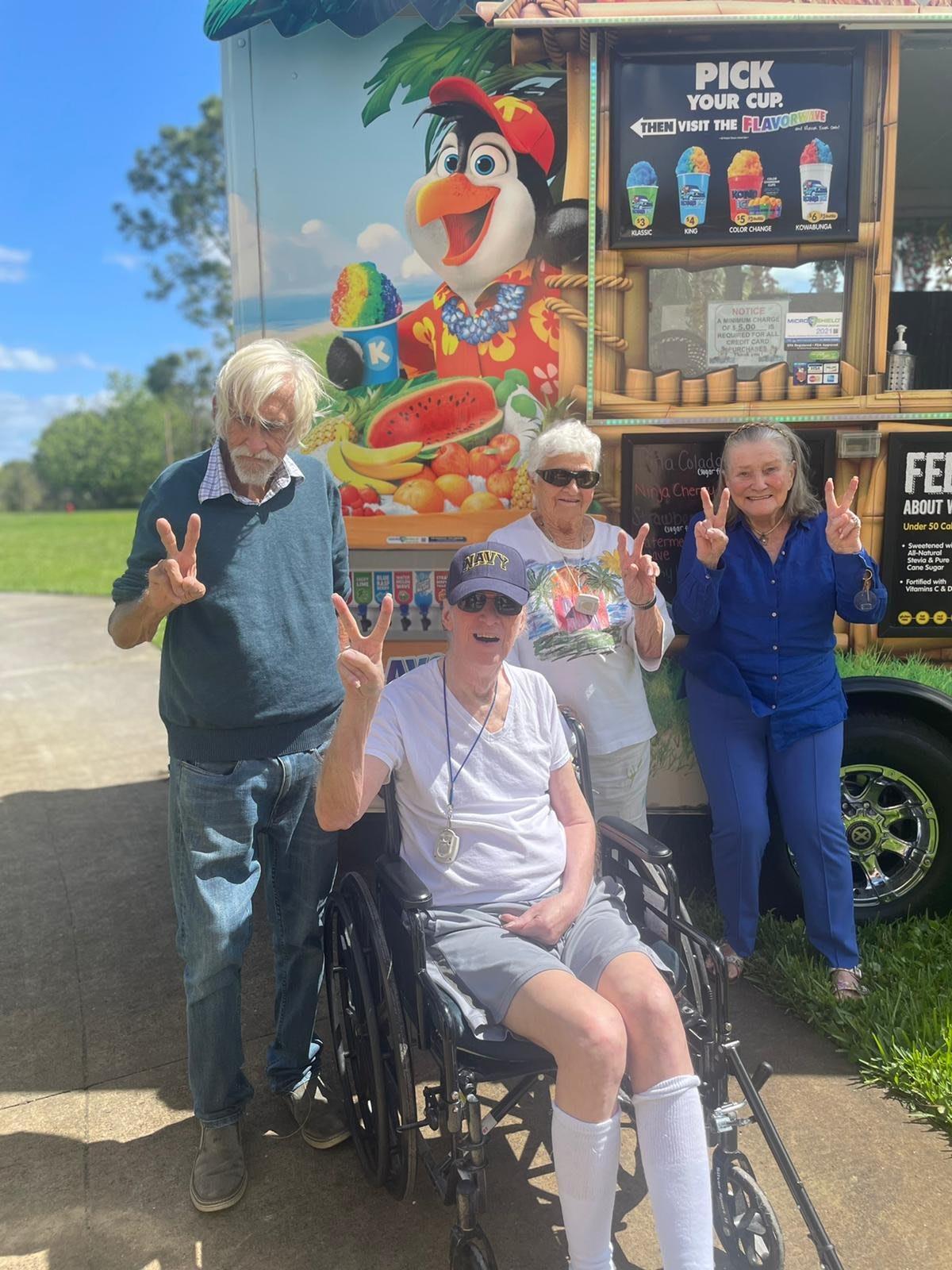 A group of elderly people enjoying a sunny day near an ice cream truck.