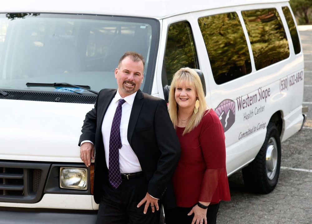 A couple in business attire standing in front of a white van.