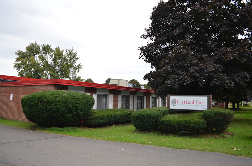 A building with a prominent sign, surrounded by greenery and under a cloudy sky.