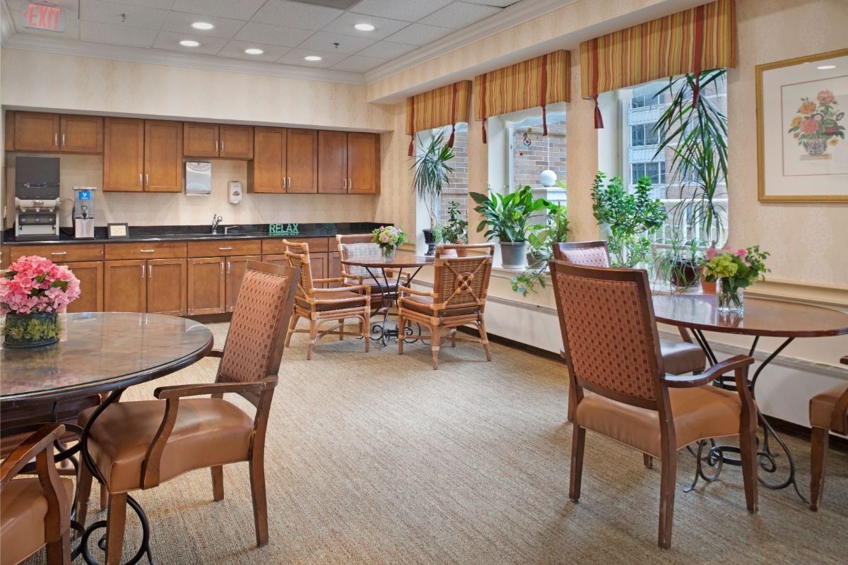 A bright and inviting dining area with wooden furniture and large windows overlooking greenery.