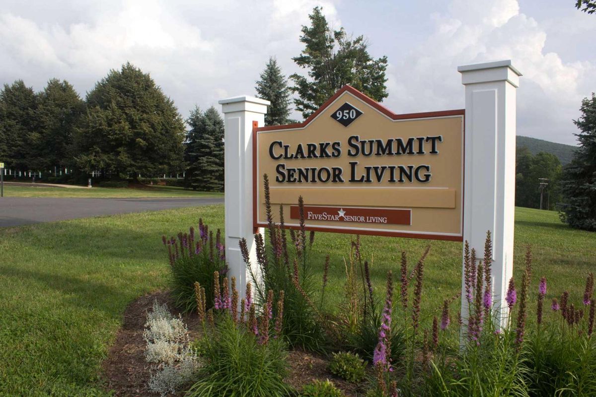 Sign for Clarks Summit Senior Living surrounded by landscaped greenery.