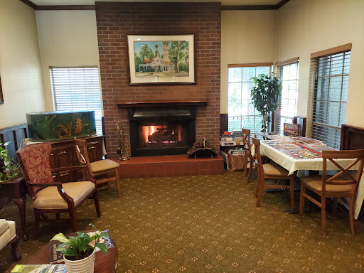 A cozy living room featuring a brick fireplace, comfortable seating, and decorative plants.