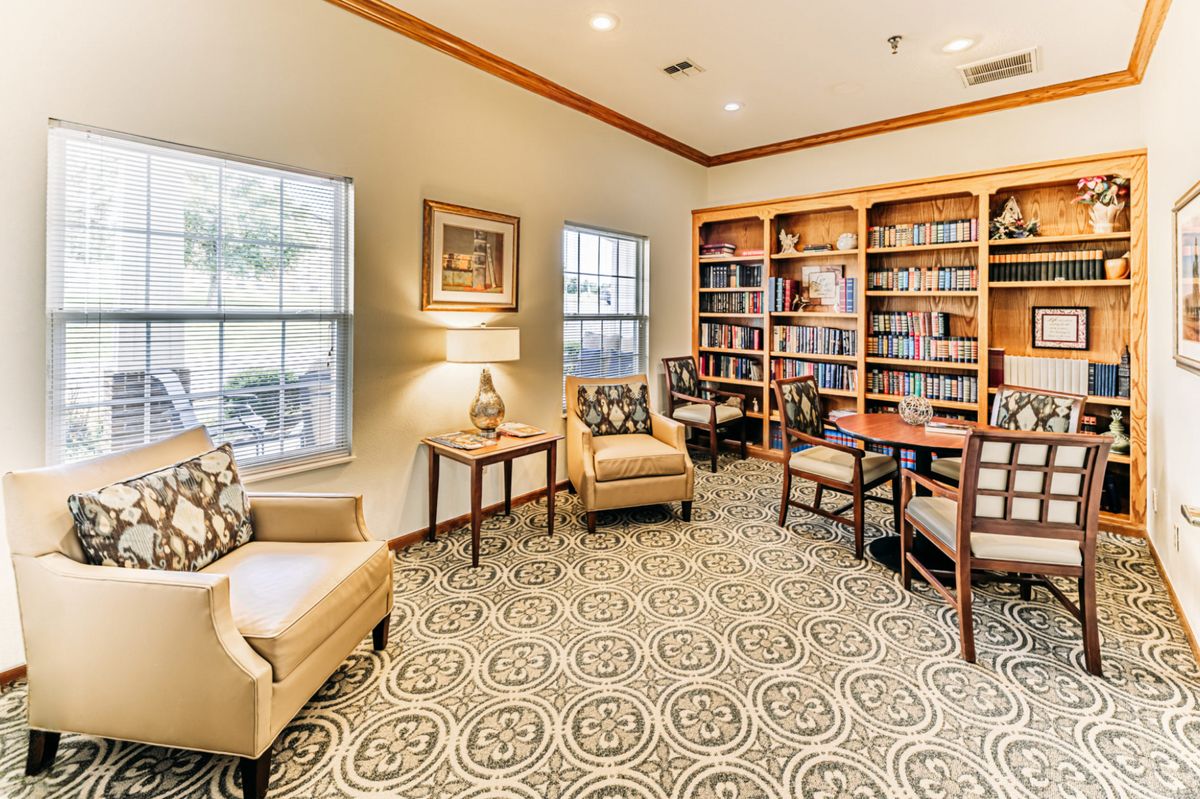 A cozy library with bookshelves, comfortable armchairs, and natural light streaming through the windows.